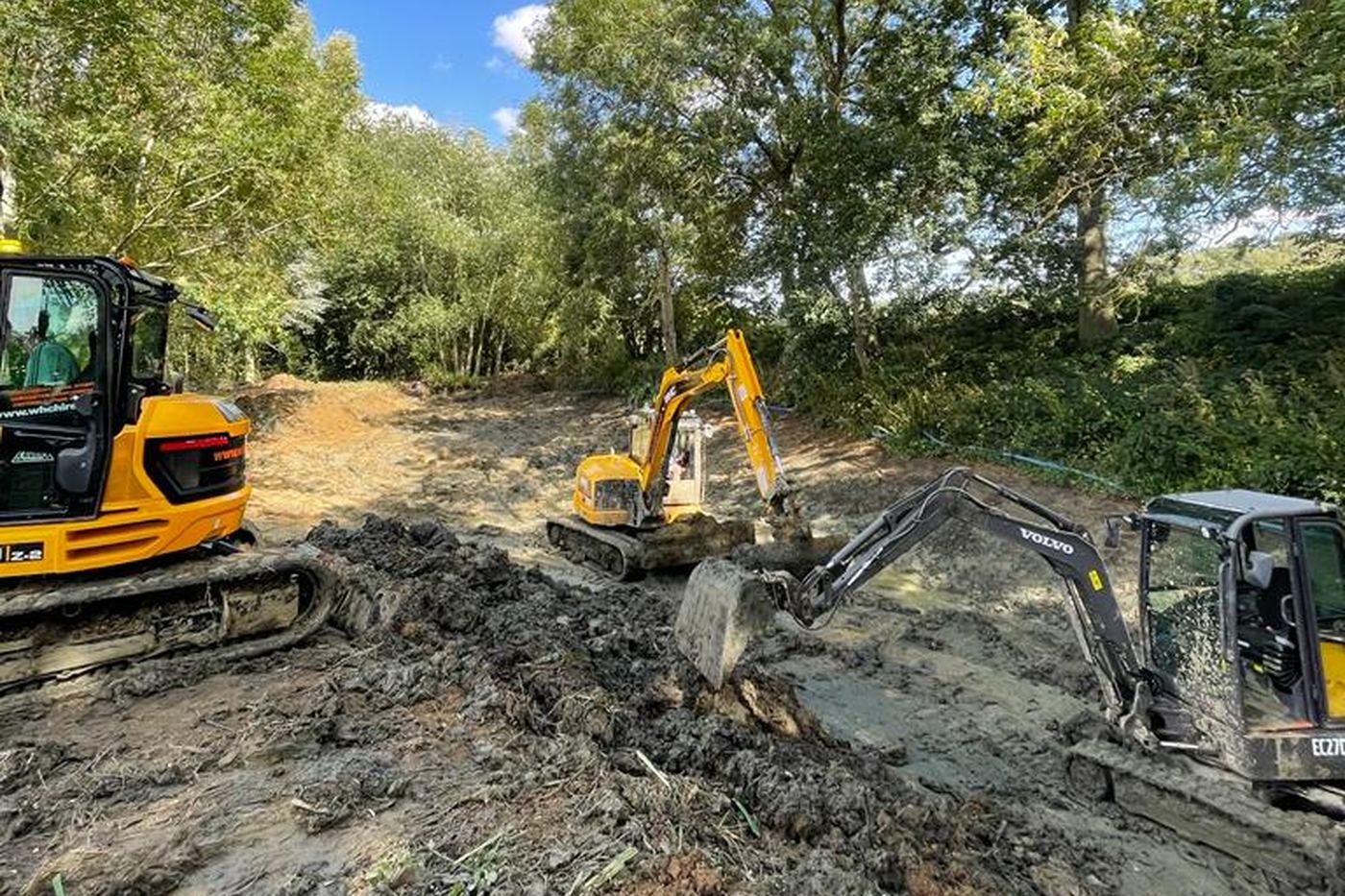 Excavators clearing and reshaping ground beside woodland in the Test Valley