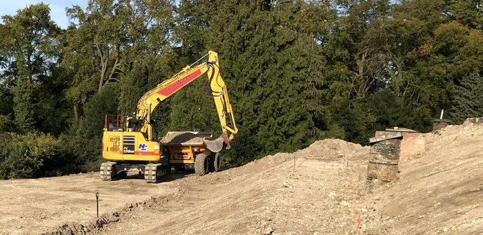 Excavator cutting a drainage run across a site