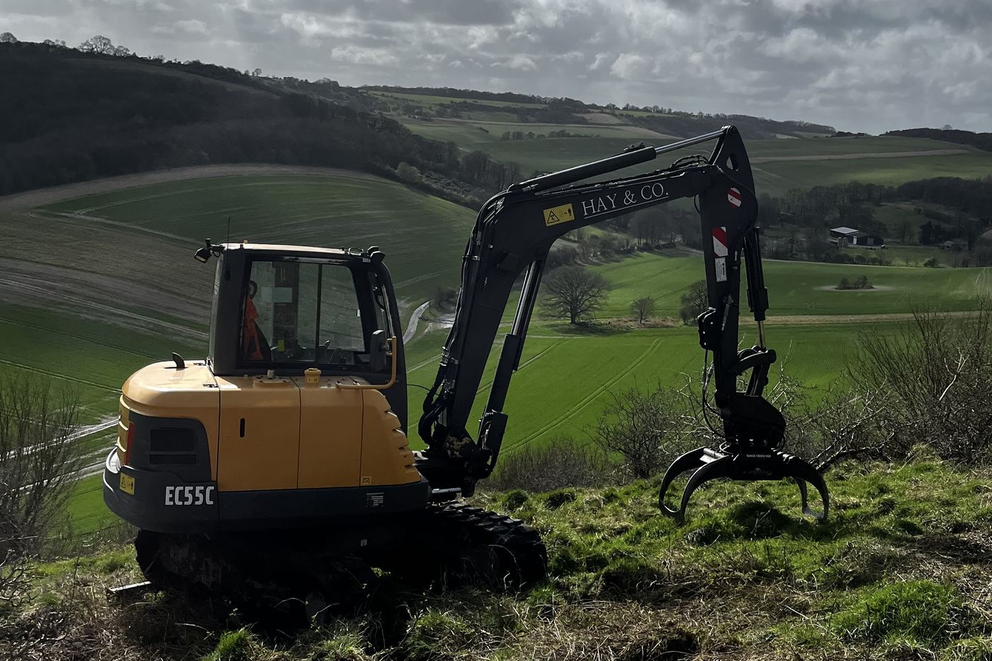 Volvo EC55C 6-tonne excavator fitted with a selector grab on a hillside clearance job