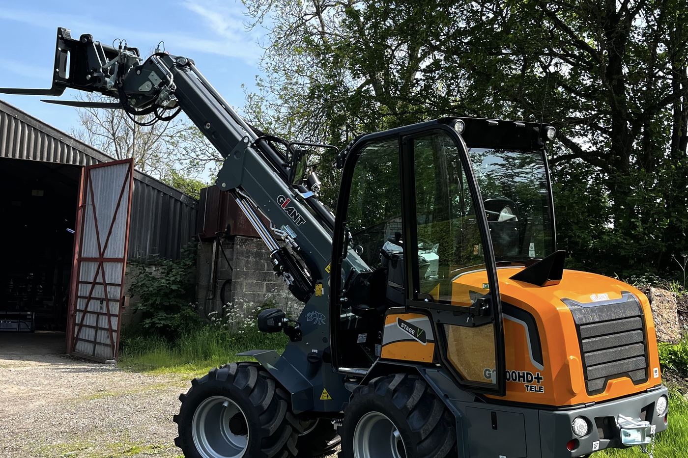 Giant G2700 HD+ pivot-steer telehandler with forks raised at a farm building